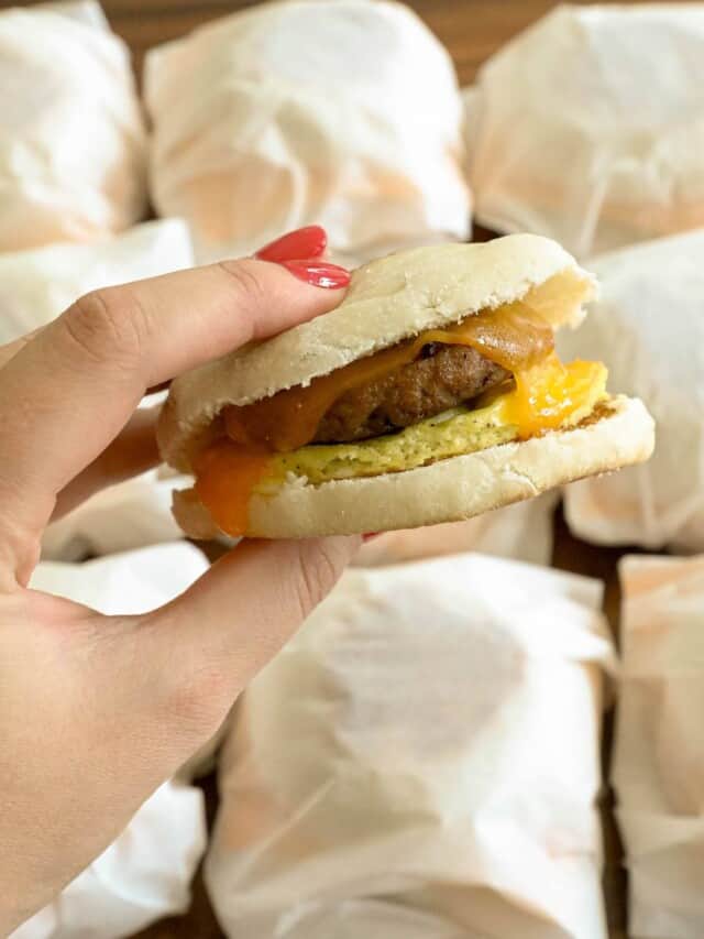 A person holding a burger in a plastic bag.