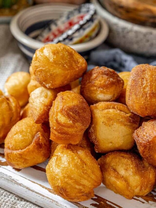 A plate full of fried doughnuts on a table.