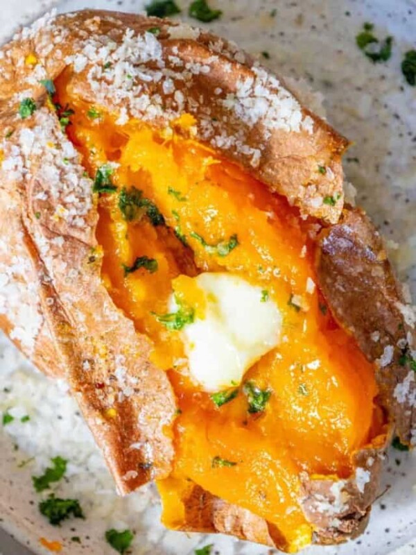 A baked sweet potato topped with butter and parsley.