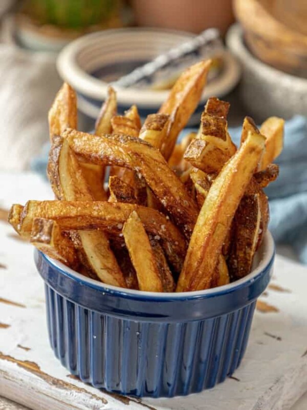 French fries in a blue bowl on a wooden table.