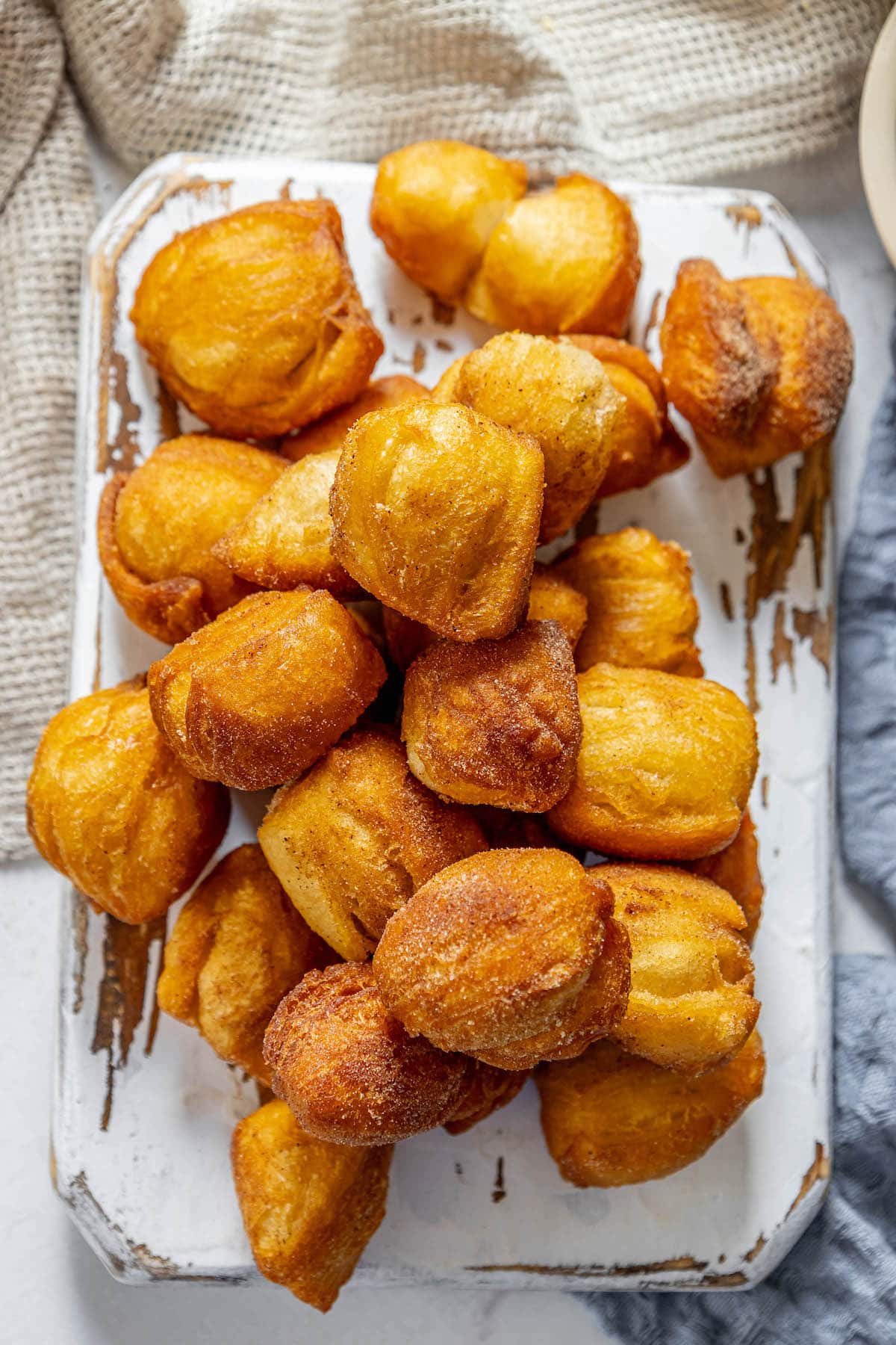A plate of fried doughnuts on a table, also known as fried cinnamon biscuits.