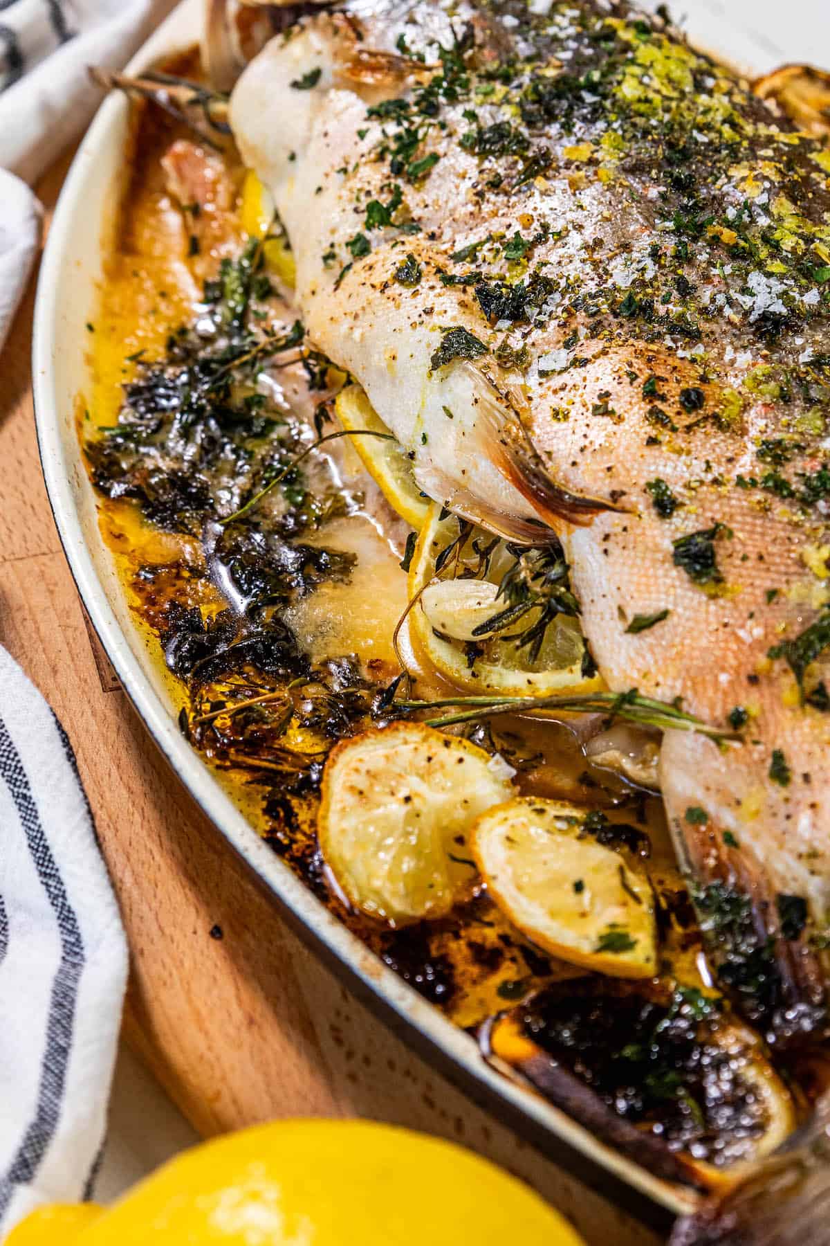 Herb-stuffed baked fish on a plate.