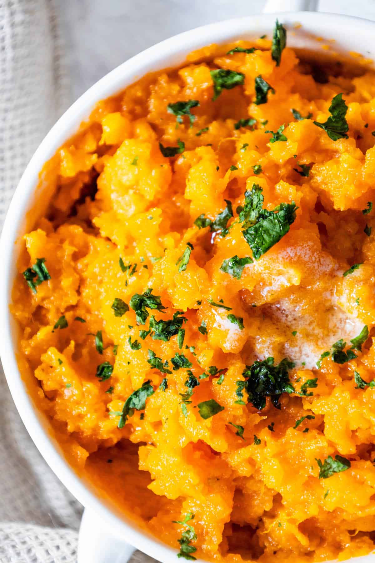 A bowl of mashed sweet potatoes with parsley.