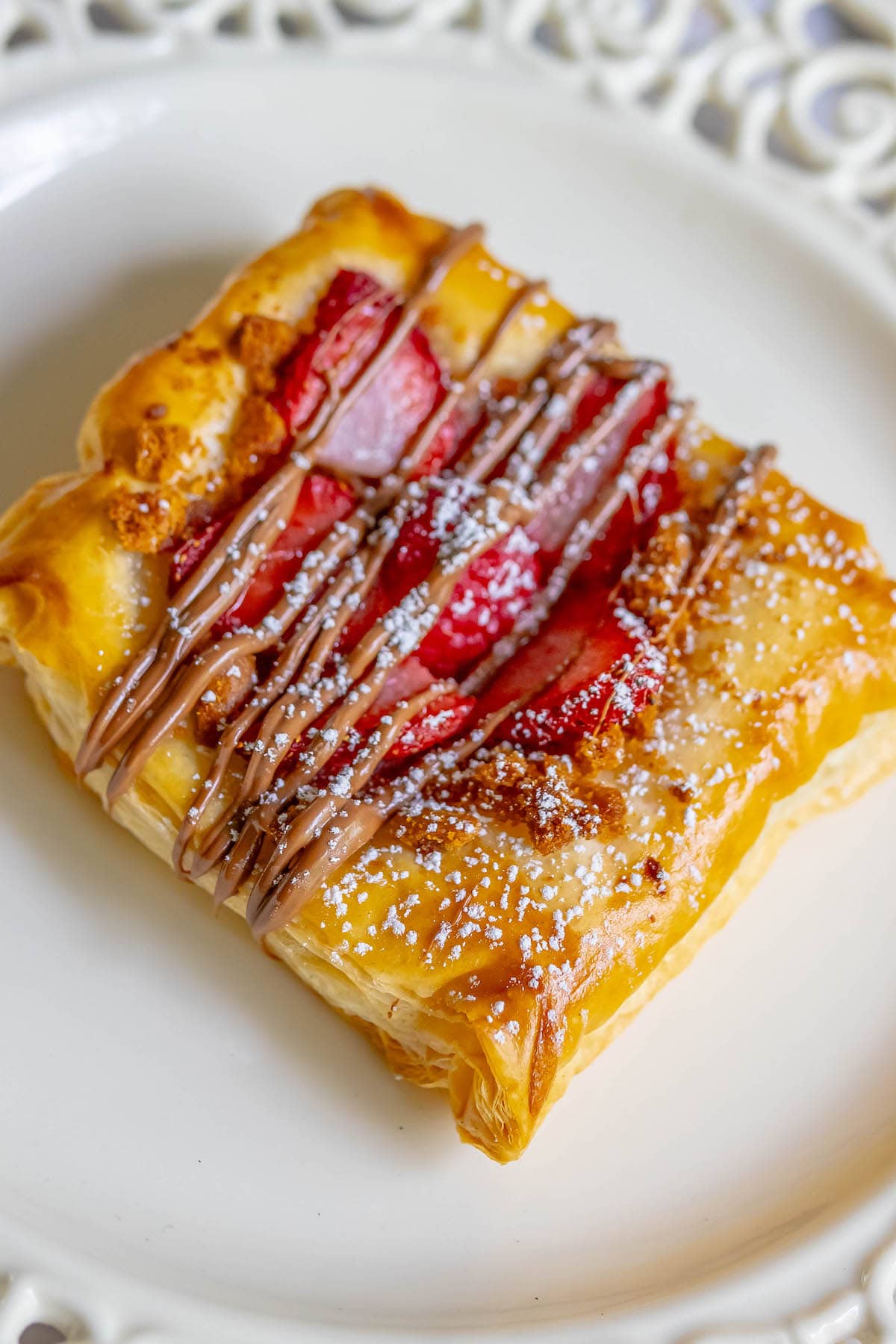 baked fruit tart on a table with berries and drizzled nutella on top