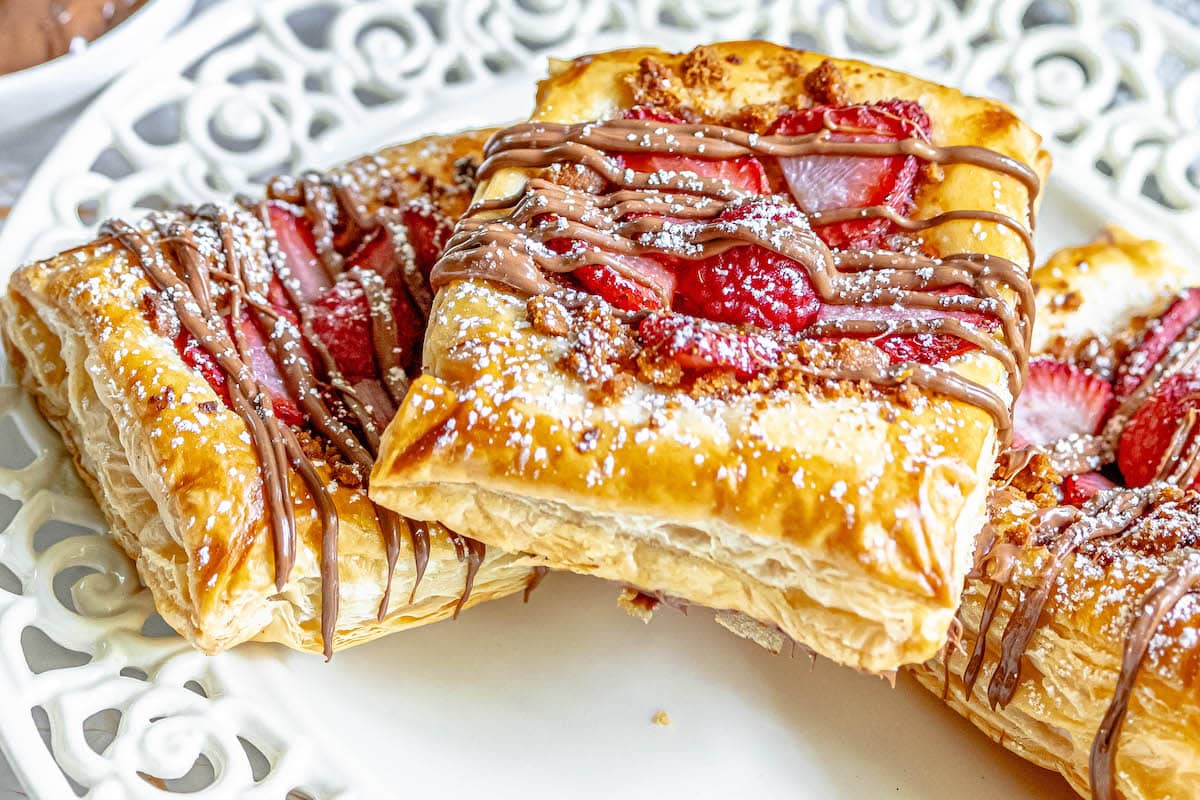 baked fruit tart on a table with berries and drizzled nutella on top