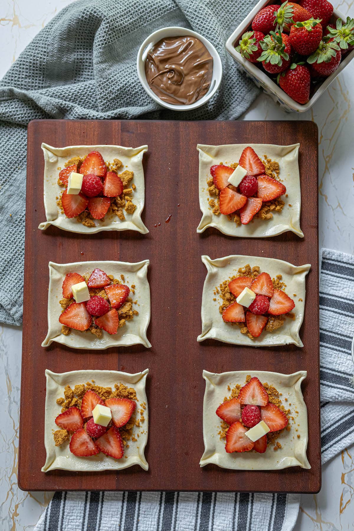 six pieces of pusff pastry with crumbs, strawberries, and cinnamon on them