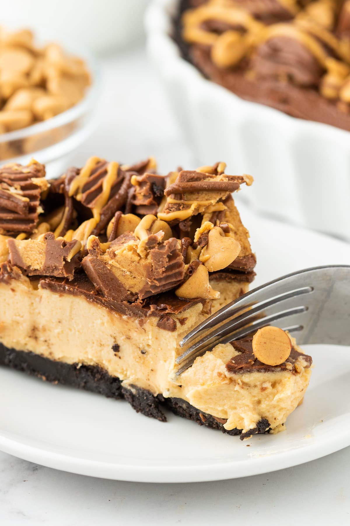 folk going into a pie with chocolate crust, creamy filling, and chocolate on it with peanut butter cups