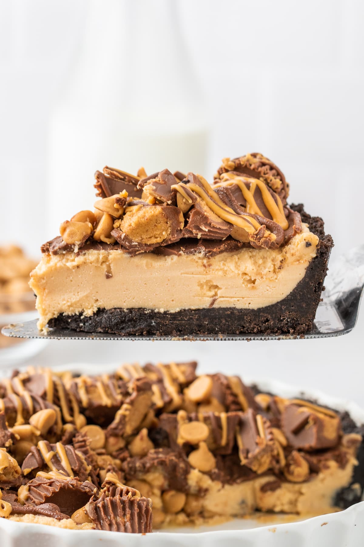 a piece of peanut butter filled chocolate crusted pie with peanut butter cups on it slice over the pie