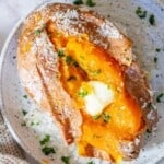 A salt-baked sweet potato with butter and parsley on a plate.