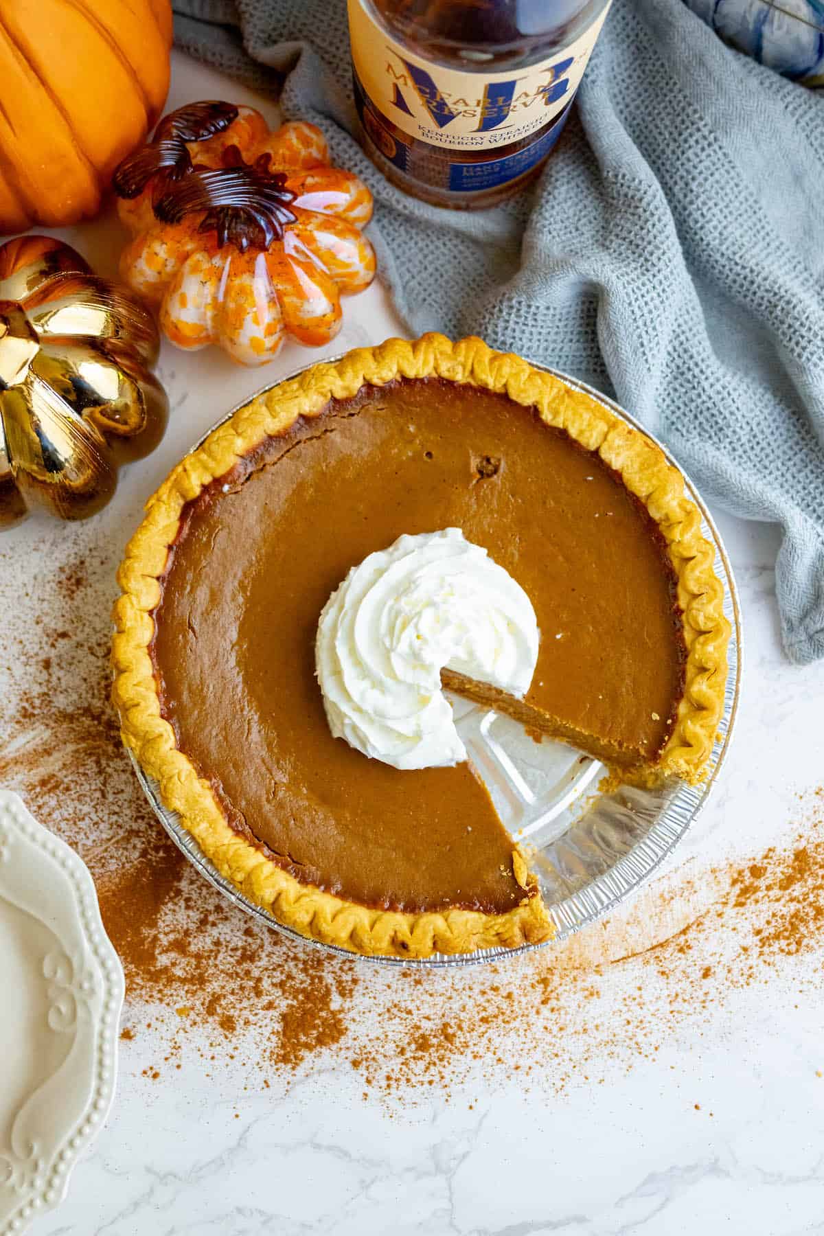 A slice of spicy pumpkin pie with whipped cream on top.