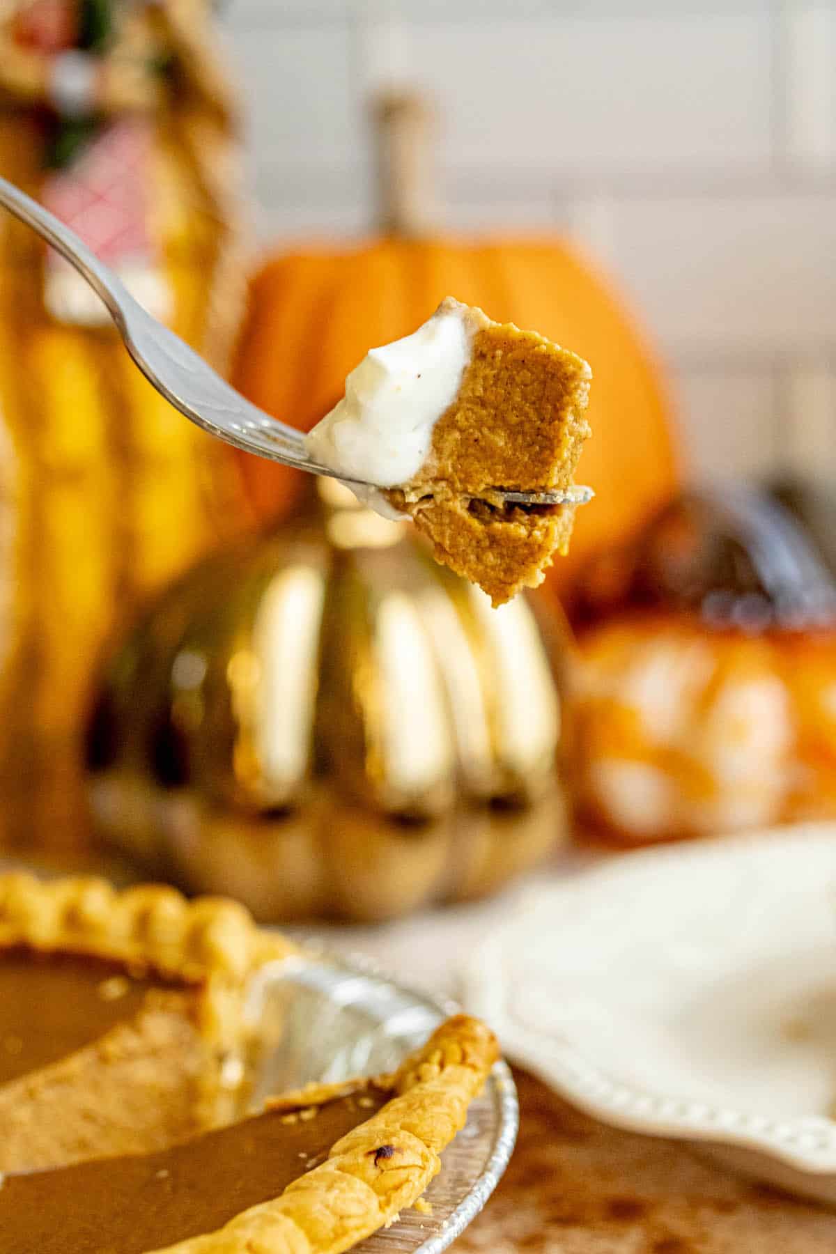 A fork is being used to take a bite out of a spicy pumpkin pie.