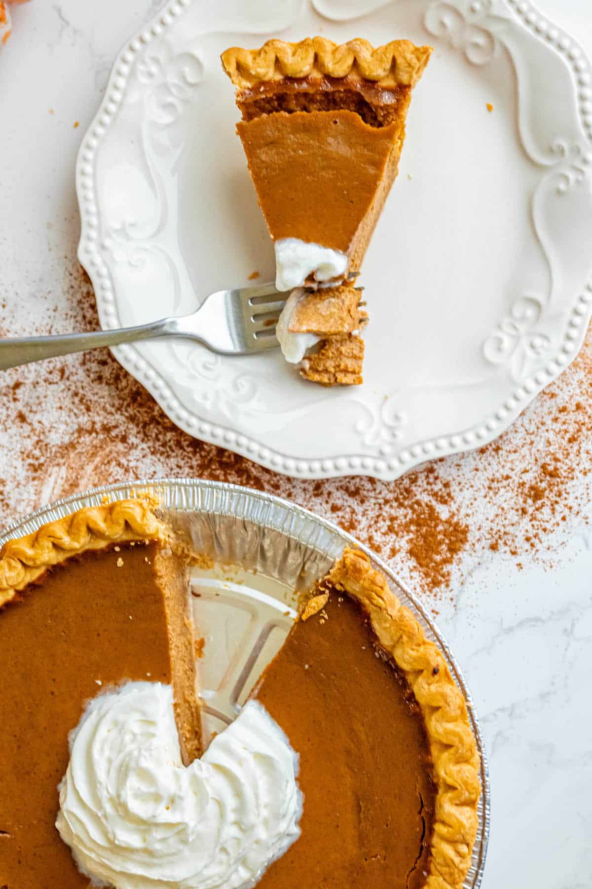A slice of spicy bourbon pumpkin pie with whipped cream and a fork.