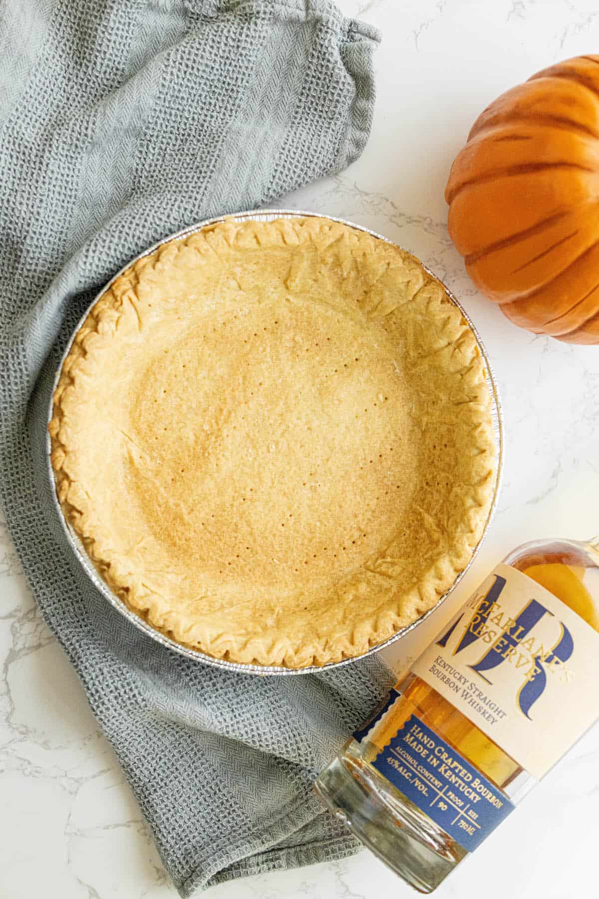 A spicy pumpkin pie on a table next to a bottle of bourbon.