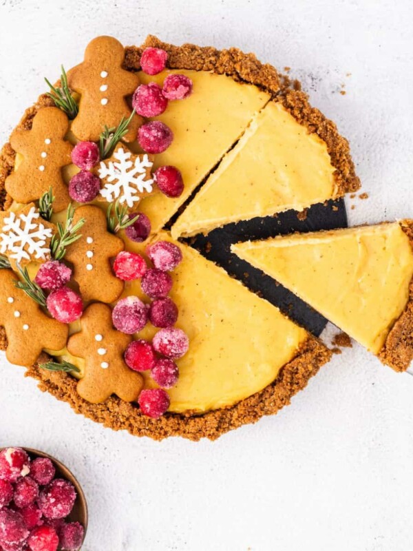 A gingerbread pie with cranberries and a slice taken out.