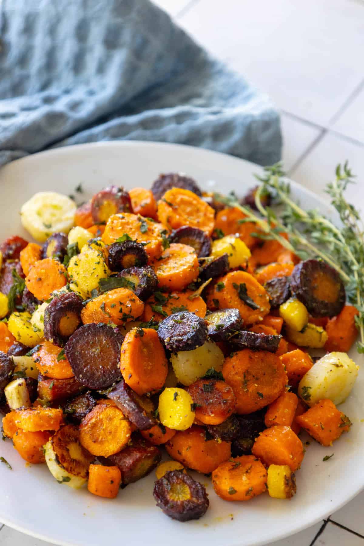 Garlic herb roasted vegetables on a white plate with sprigs of thyme.