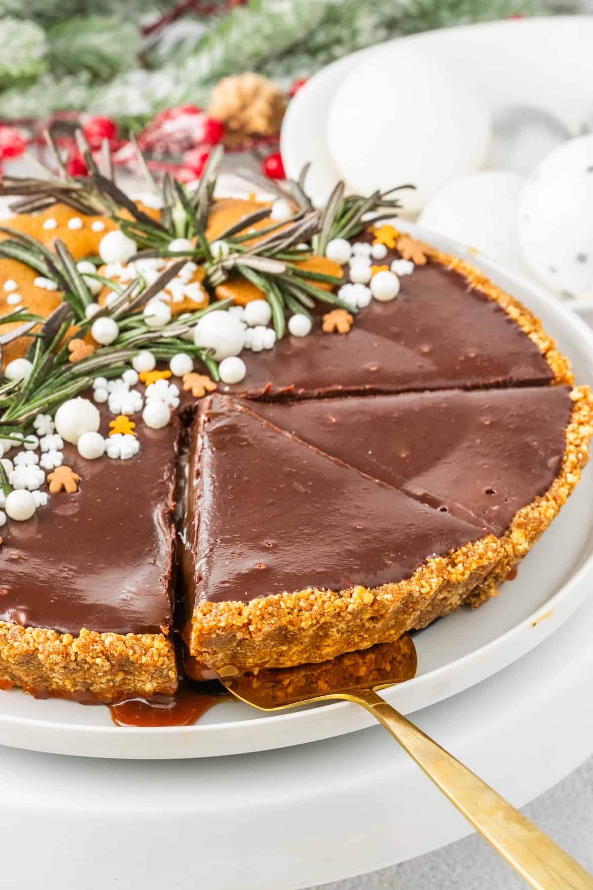A gingerbread chocolate tart with rosemary on a plate.