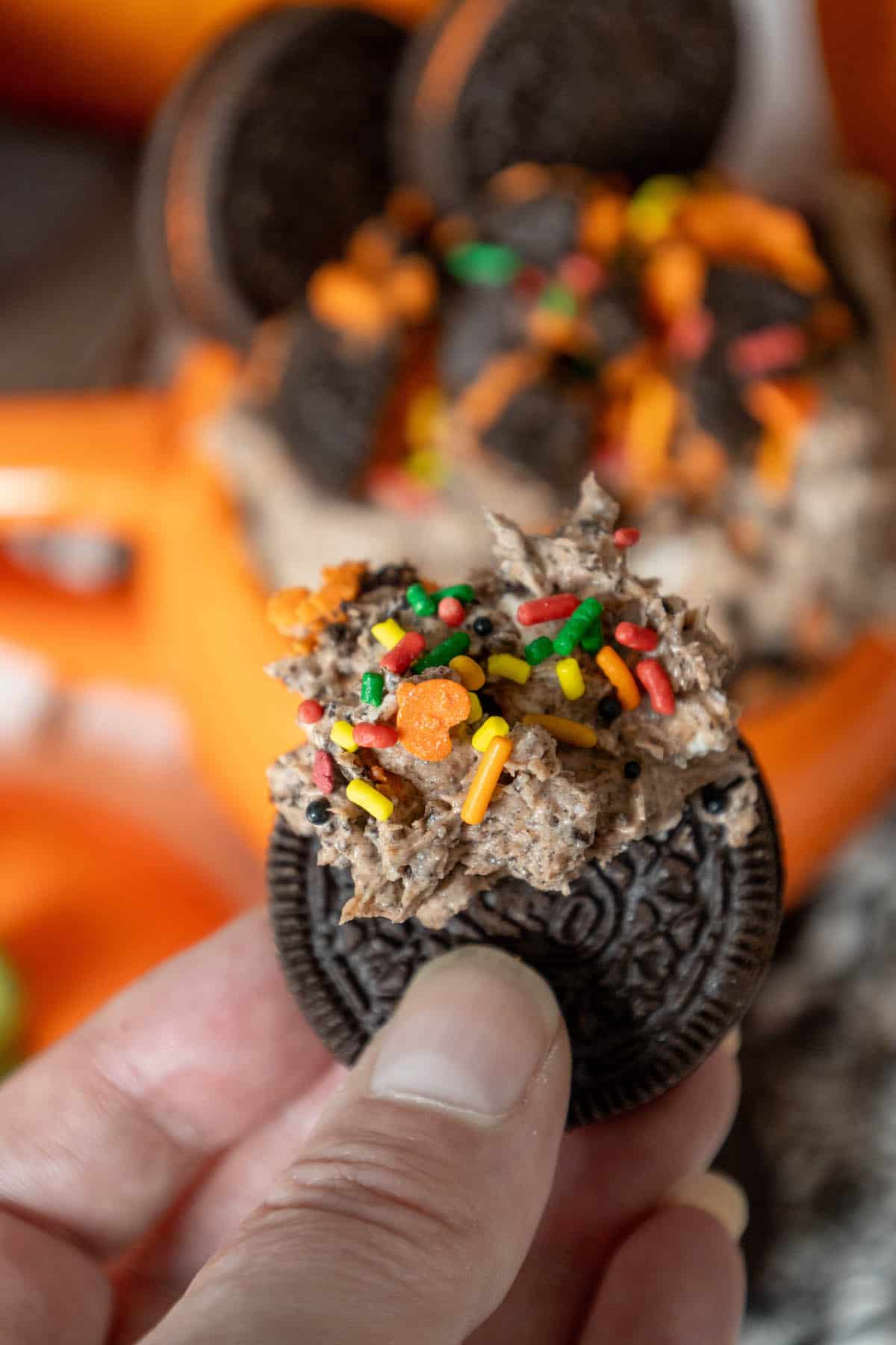 A person holding a Halloween Oreo cookie