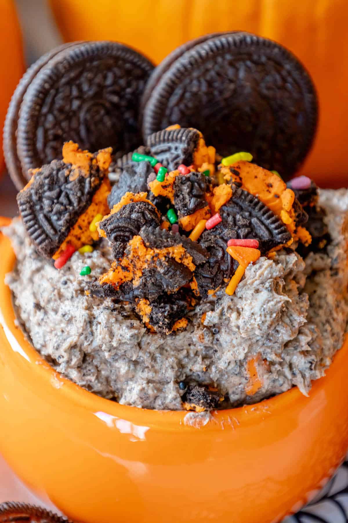 Halloween oreo dip in an orange bowl with sprinkles and oreos.
