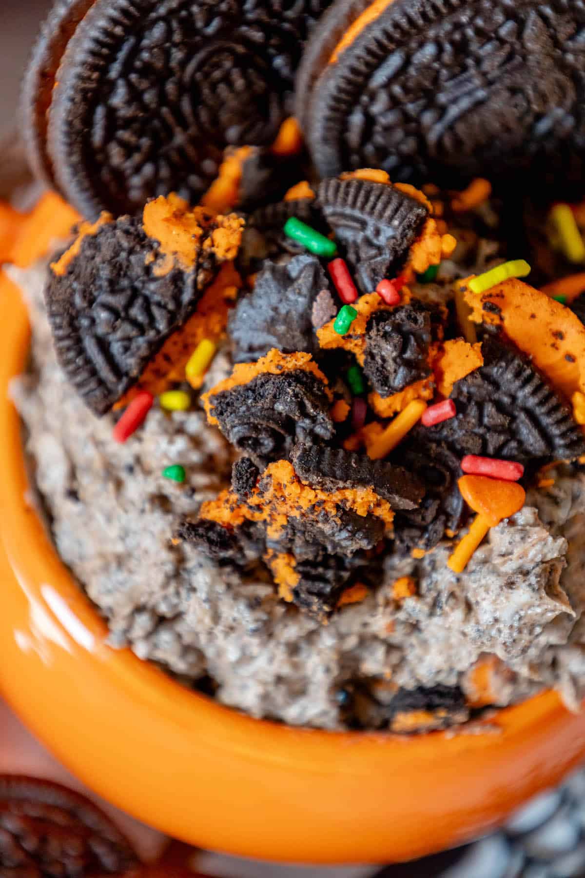 Halloween Oreo cookie dip in an orange bowl with sprinkles.