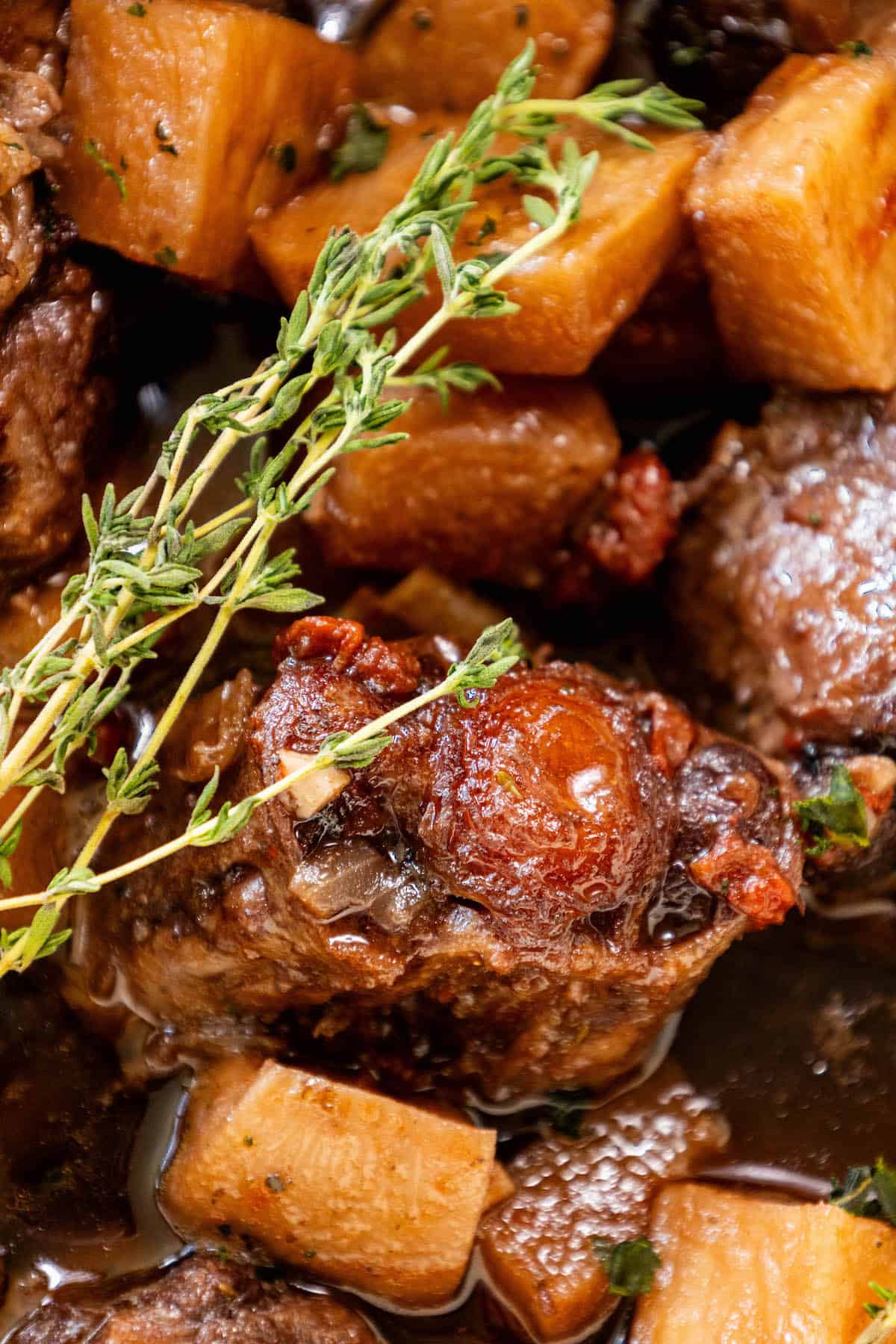 Roasted oxtail stew with potatoes and sprigs of thyme.
