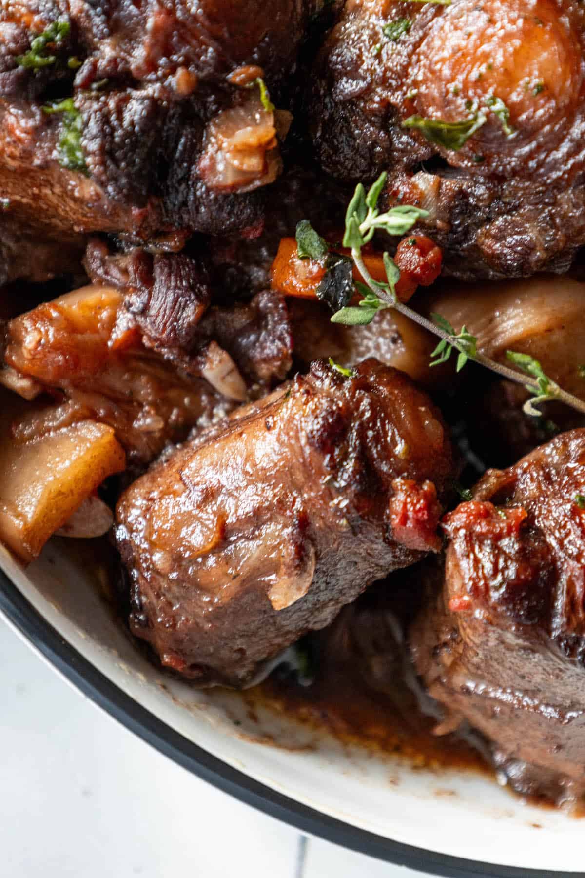 A bowl of stewed beef with apples and thyme, cooked as a Roasted Oxtail Stew.