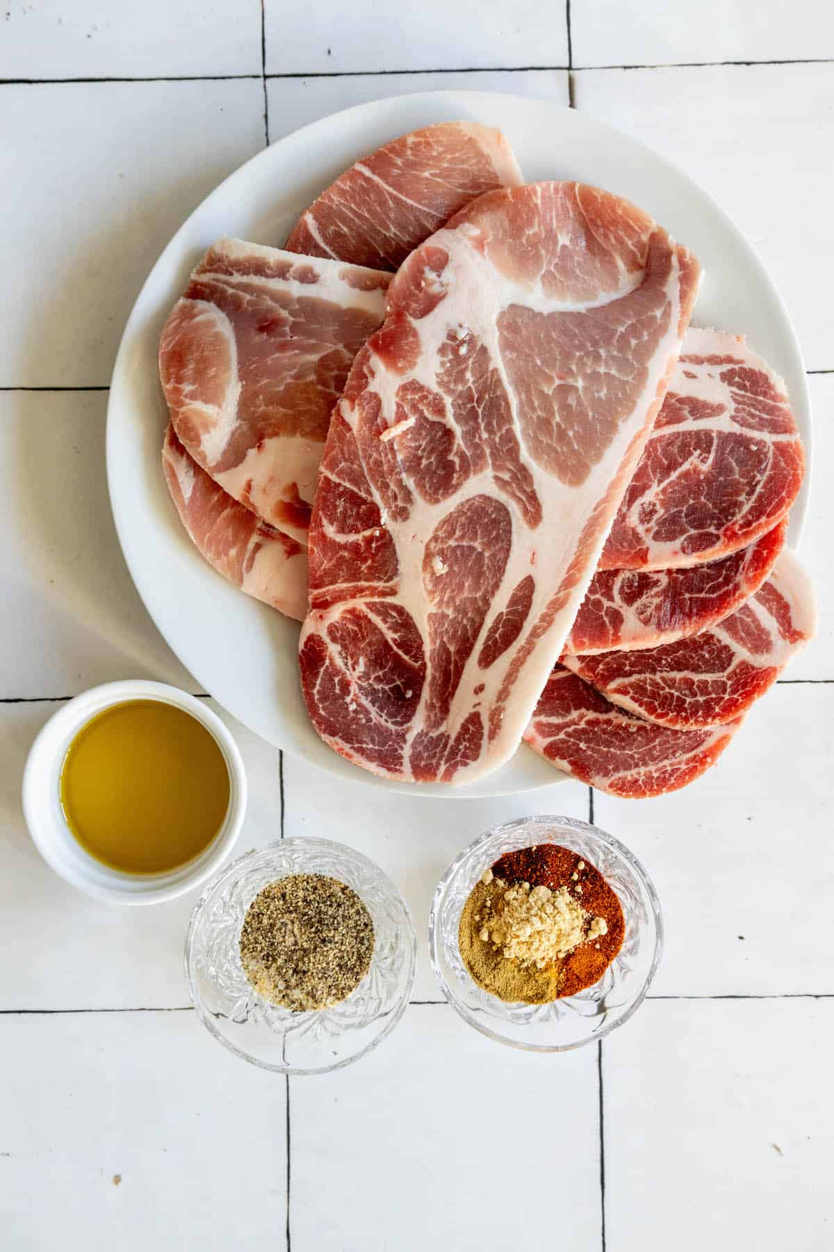 A plate of meat and condiments on a tiled floor.