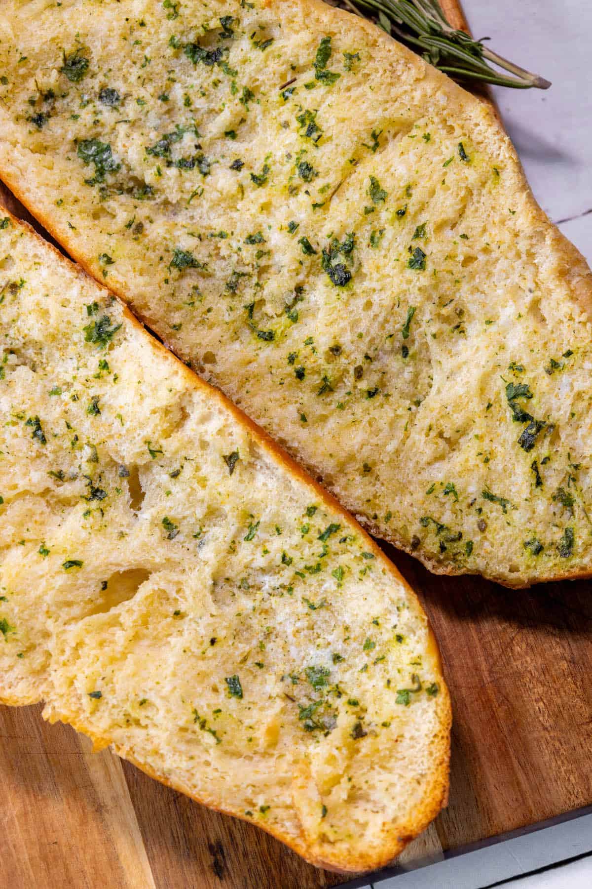 Easy garlic bread made with two slices of bread and herbs on a cutting board.