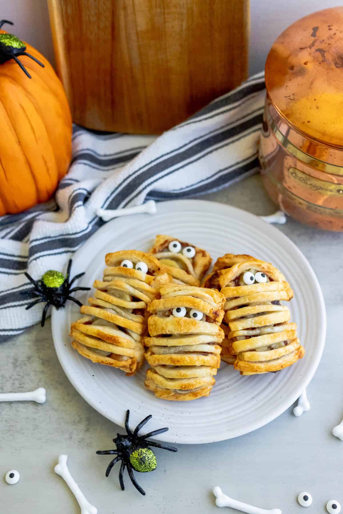Banana nutella mummies on a plate with pumpkins and spiders.