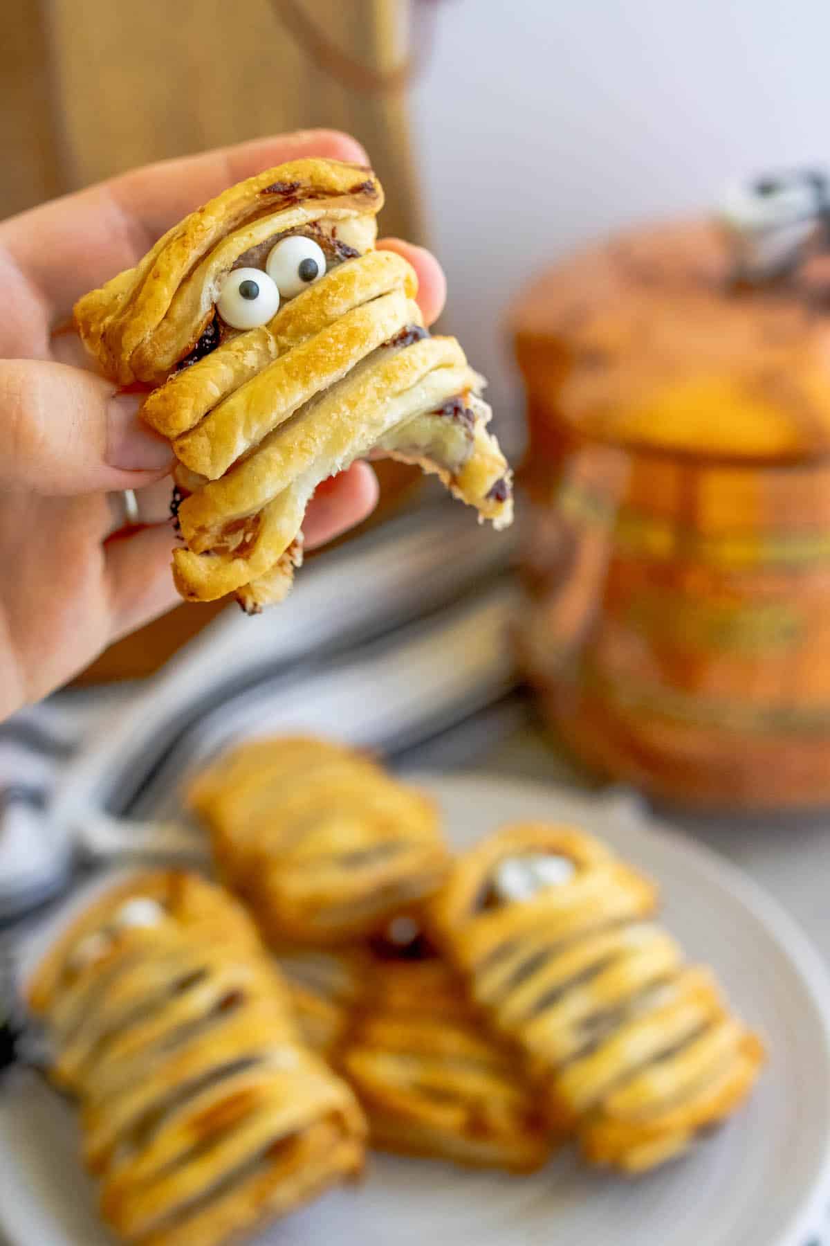 A person is holding a mummy pastry topped with banana and Nutella.