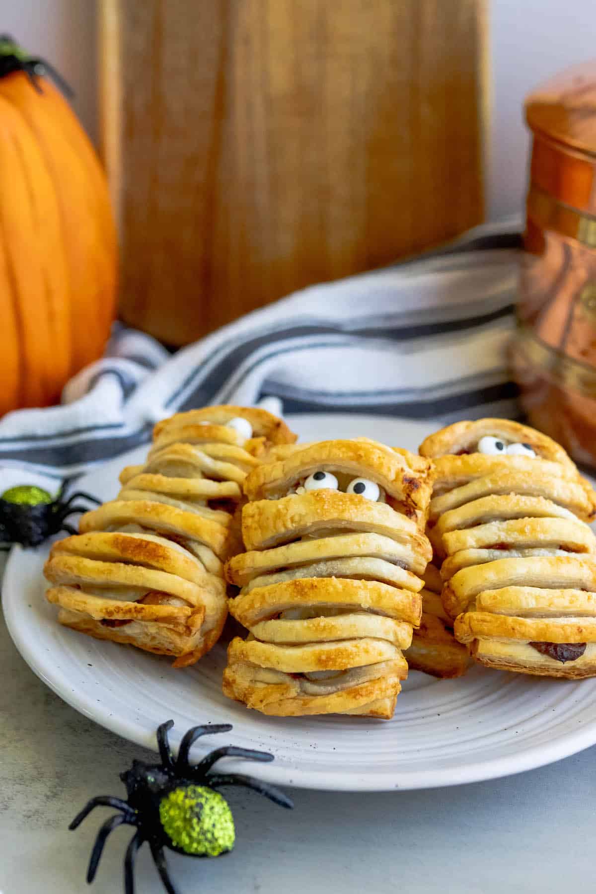 Banana nutella mummies displayed alongside pumpkins and spiders on a plate.