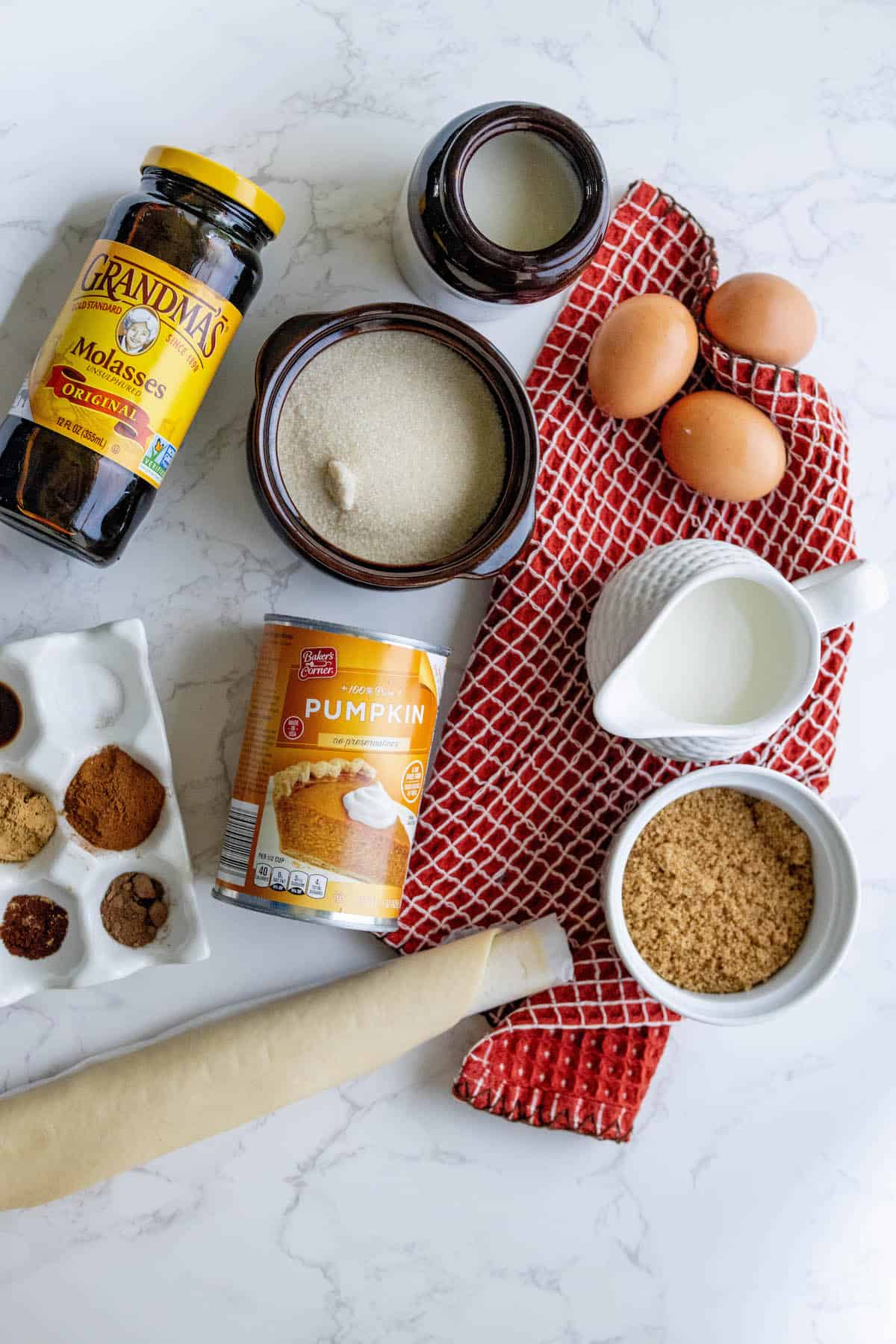 The ingredients for a delicious pumpkin pie are neatly organized on a marble table.
