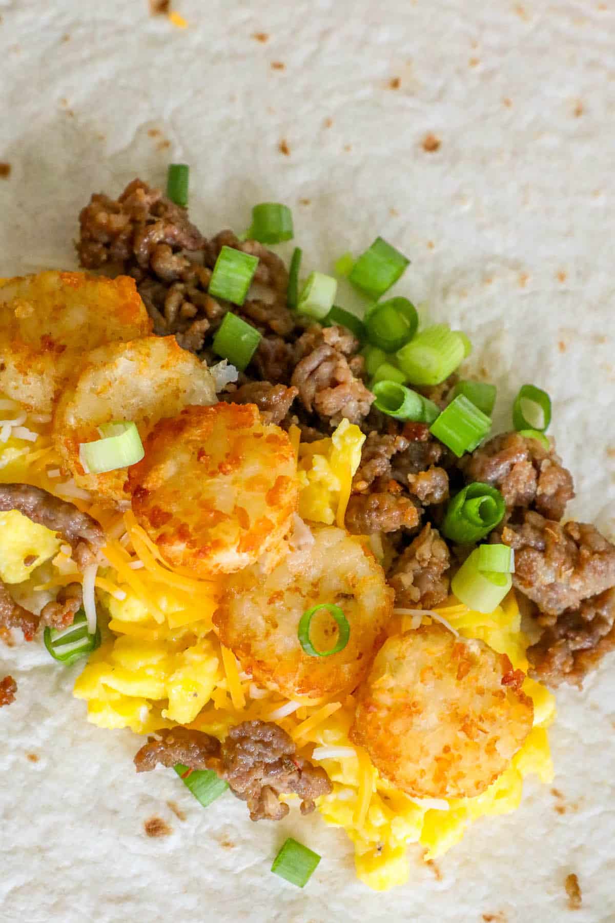 A freezer breakfast burrito with eggs, sausage, and green onions.