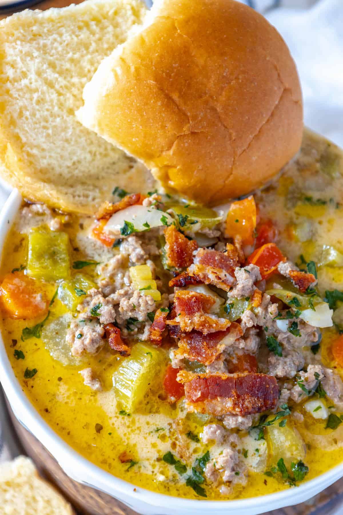 A cheesy bowl of Cheeseburger Soup with meat, vegetables, and bread.
