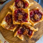 Cranberry pecan tarts served on a wooden cutting board.