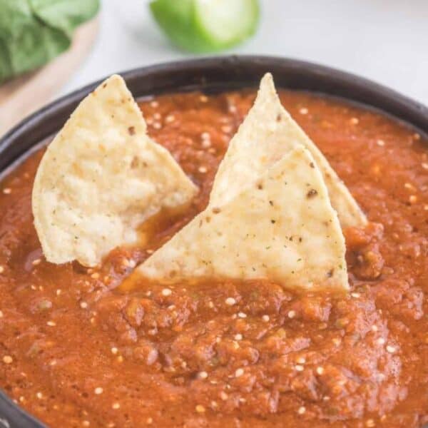 A bowl of mexican sauce with tortilla chips.