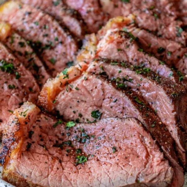 Beef tenderloin on a plate with herbs.