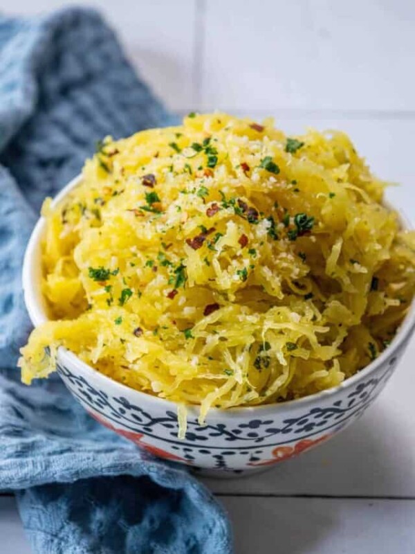 A bowl of spaghetti squash with parmesan cheese and parsley.