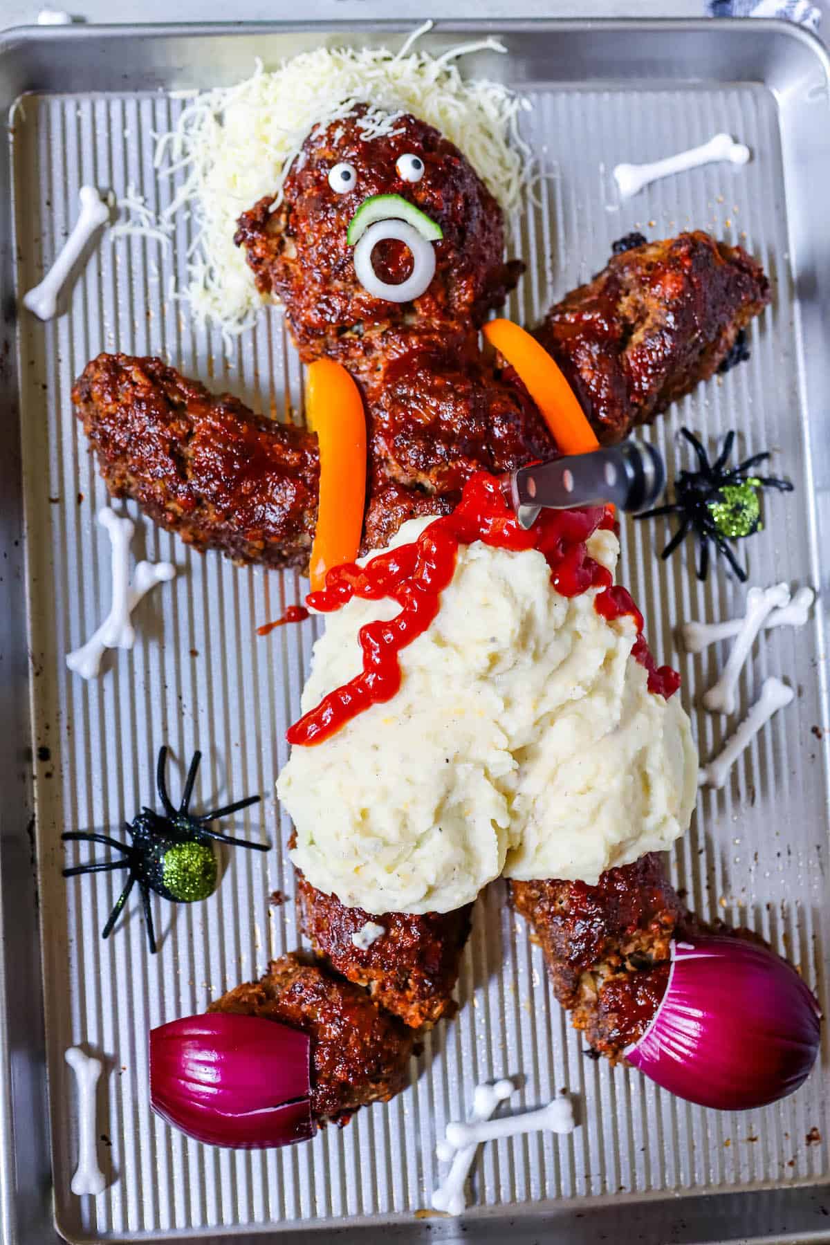 A metal pan with a stuffed teddy bear on it, resembling a whimsical yet macabre dead man meatloaf.