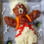 A dead man meatloaf on a tray with mashed potatoes and carrots.