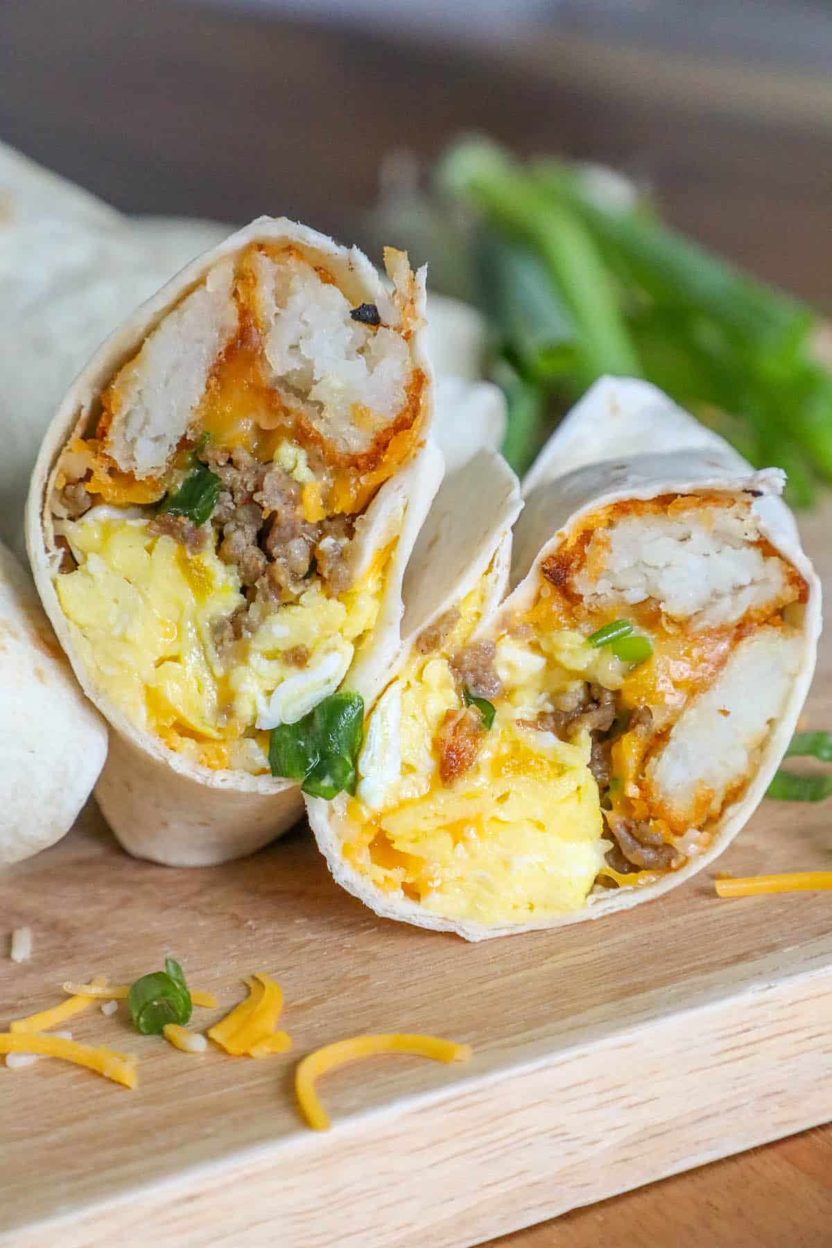 Freezer breakfast burritos with eggs and cheese on a cutting board.
