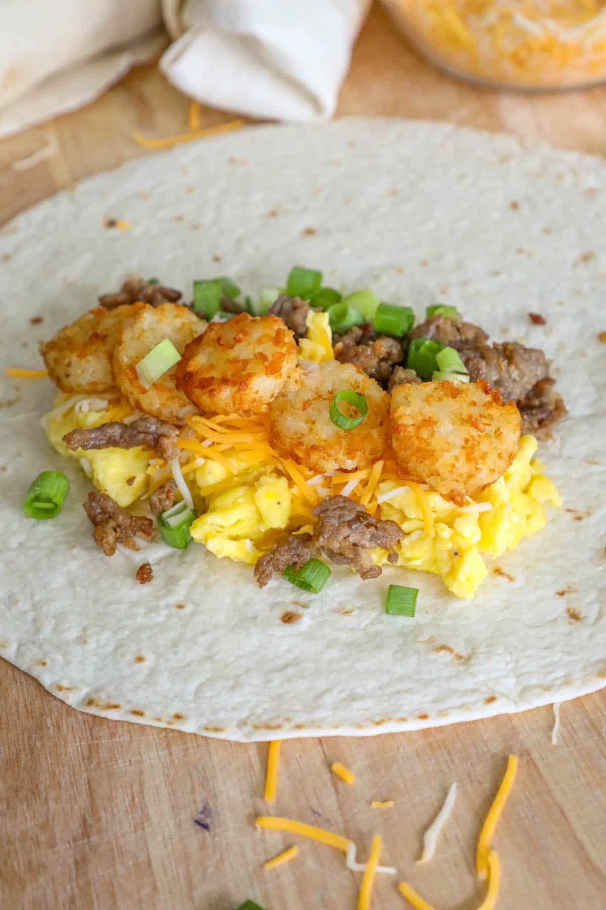 A freezer breakfast burrito with eggs, sausage, and wooden cutting board.