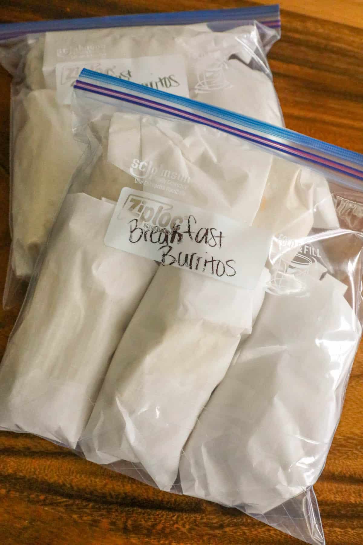 Three bags of frozen mashed potatoes sitting on a wooden table in the freezer.