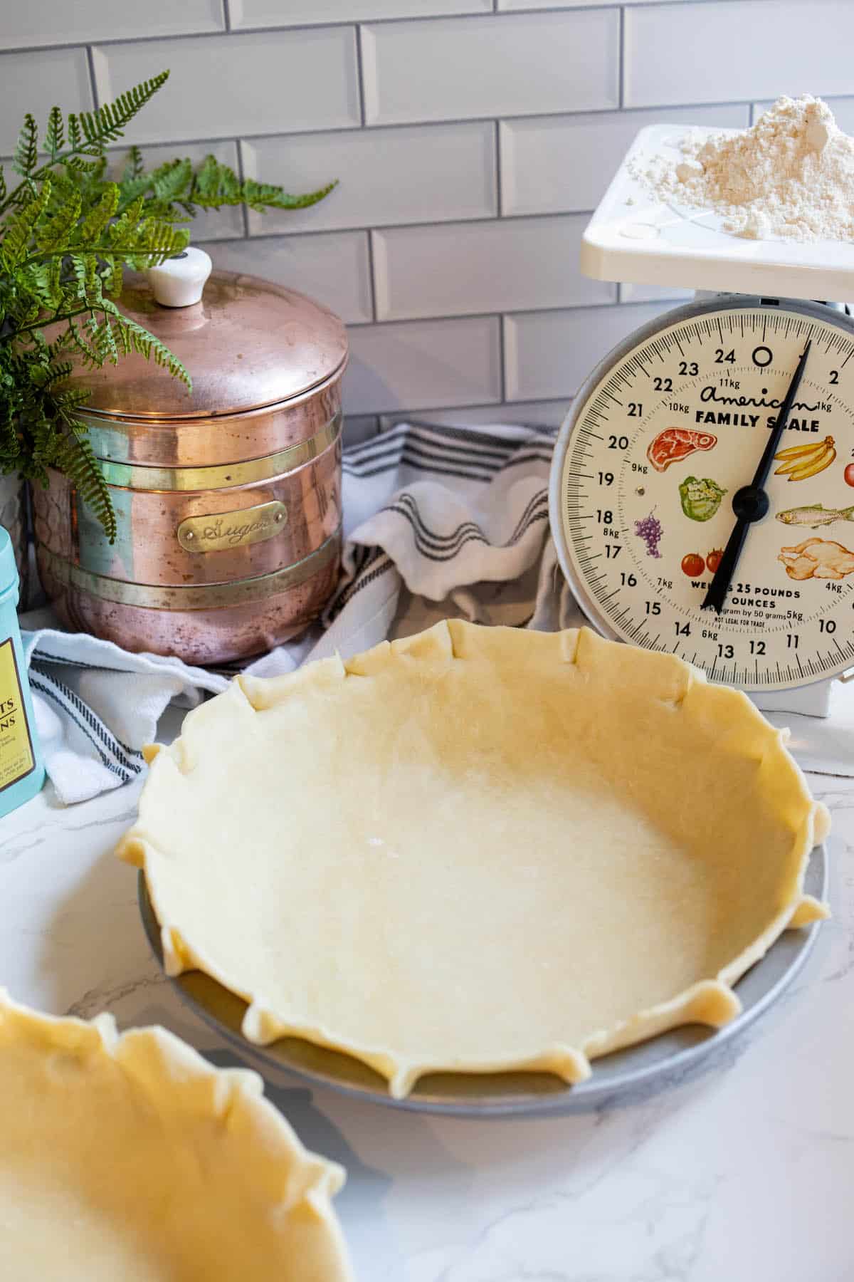 Two easy pie crusts on a counter next to a scale.