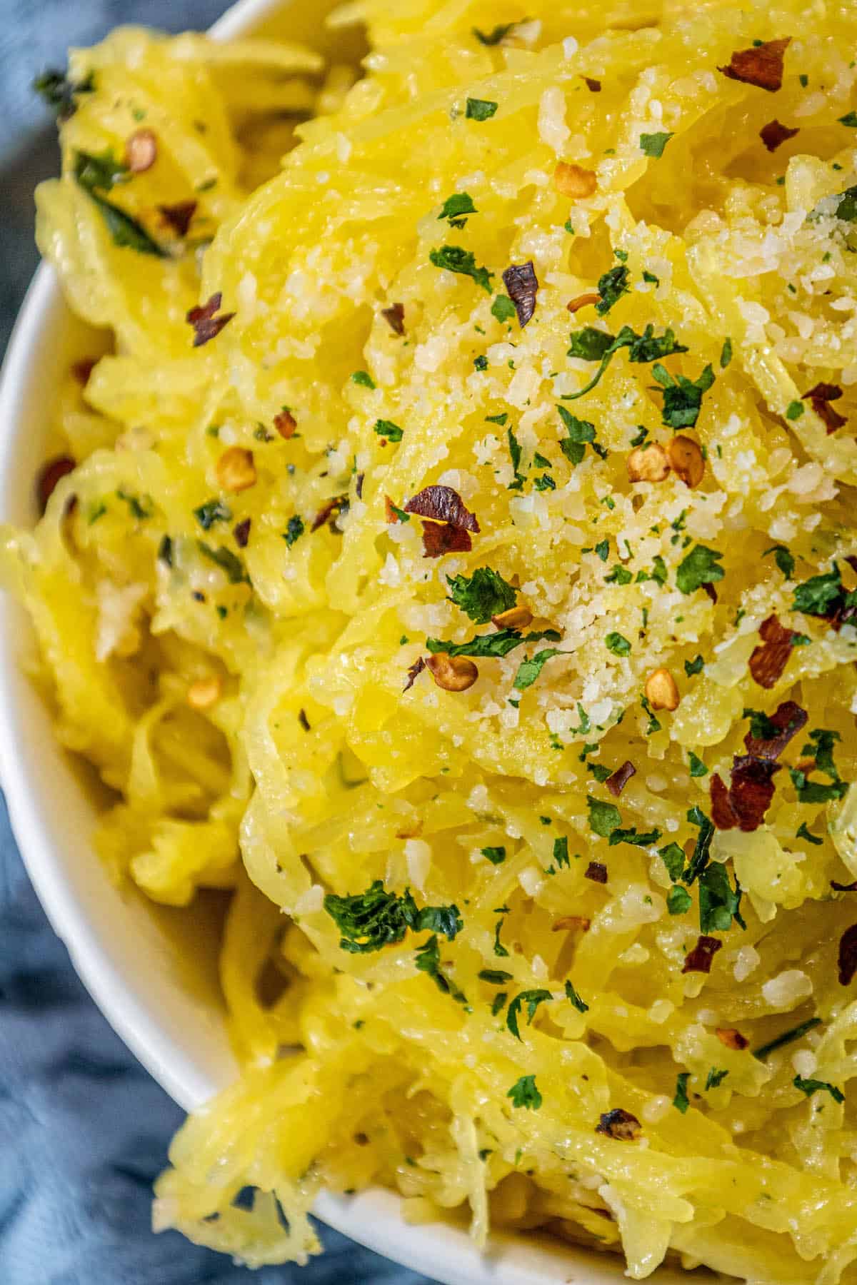 A bowl of yellow spaghetti squash with parmesan cheese and parsley.