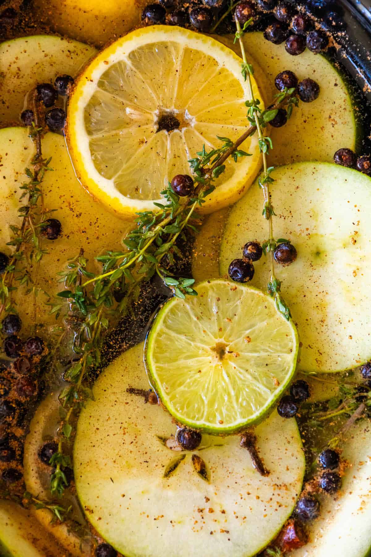 A croc containing apples, lemons and sprigs of thyme.