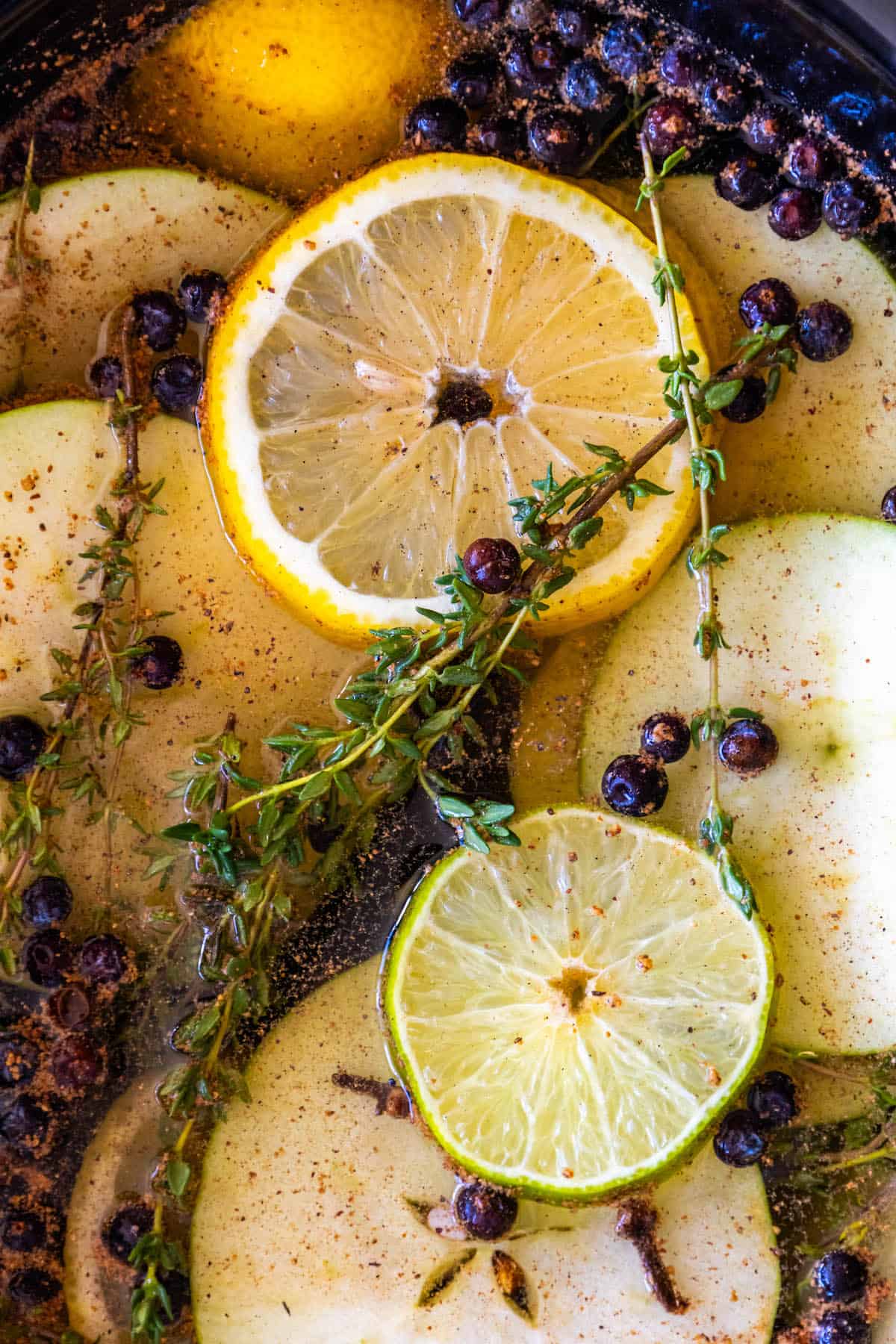 A crockpot filled with apples, pears, lemons and sprigs of thyme.