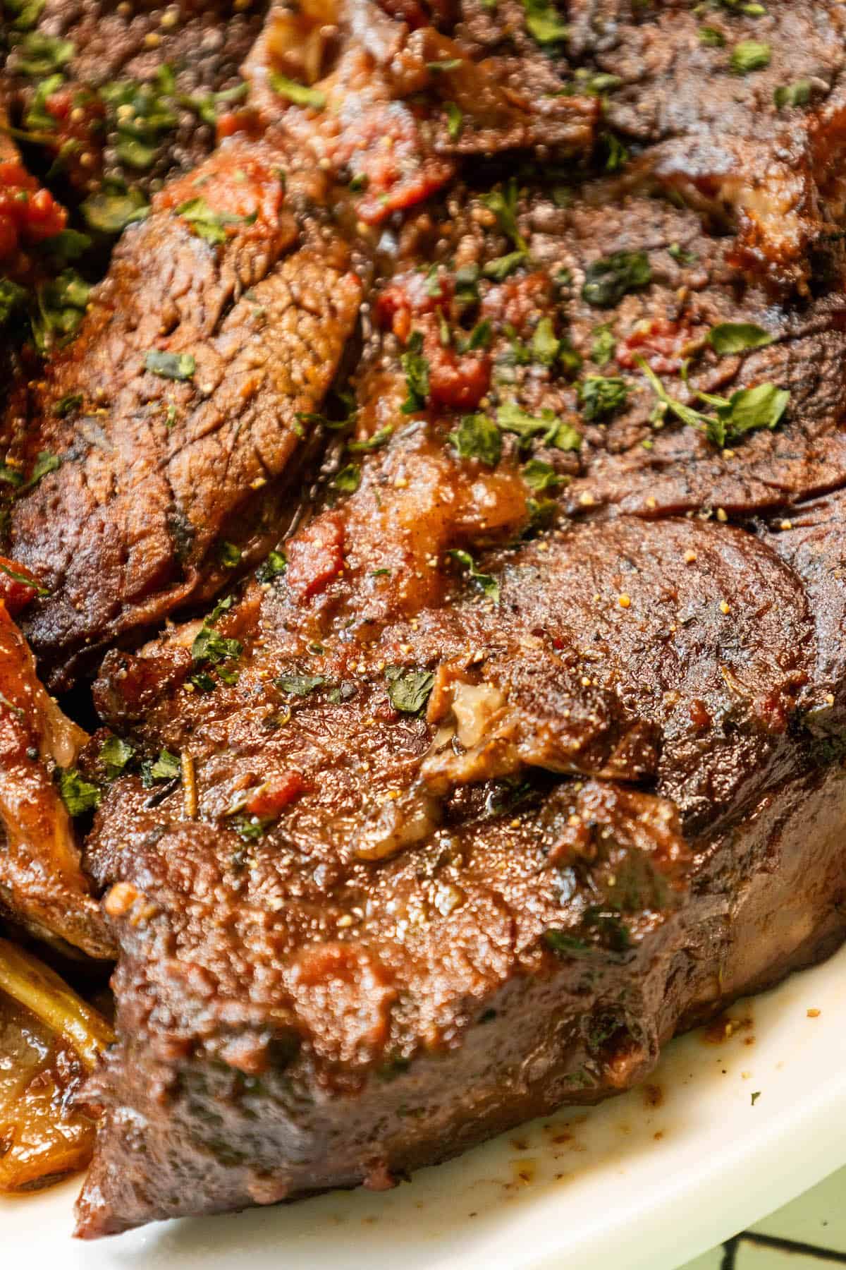 A perfect chuck roast with sauce and herbs.