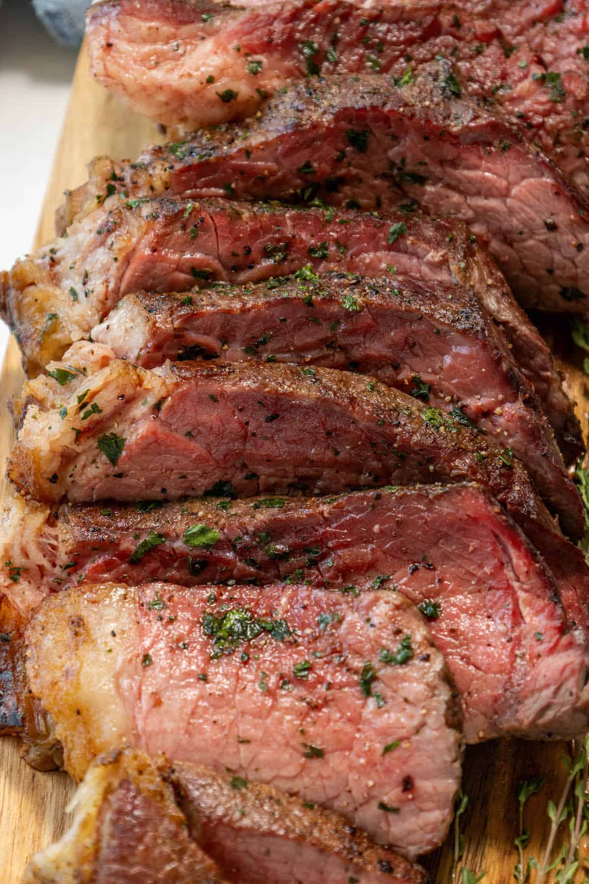 Rump roast steak on a cutting board with herbs.