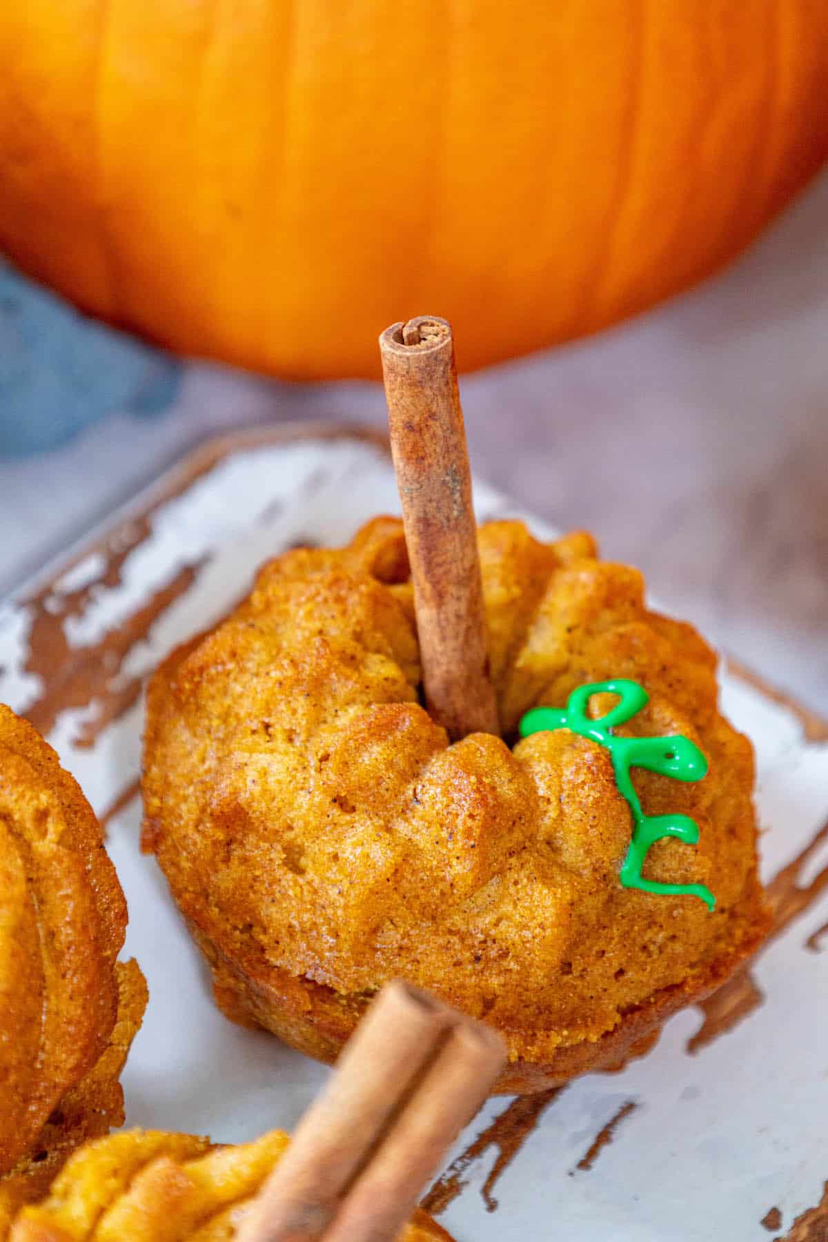 Halloween pumpkin muffins with cinnamon sticks on a plate.