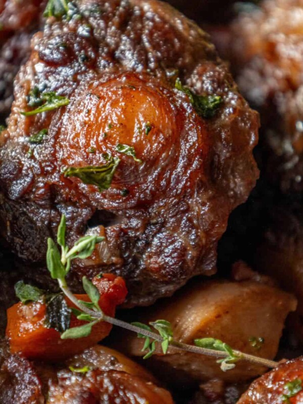 A close up of a delicious dish featuring roasted oxtail stew with potatoes and thyme.